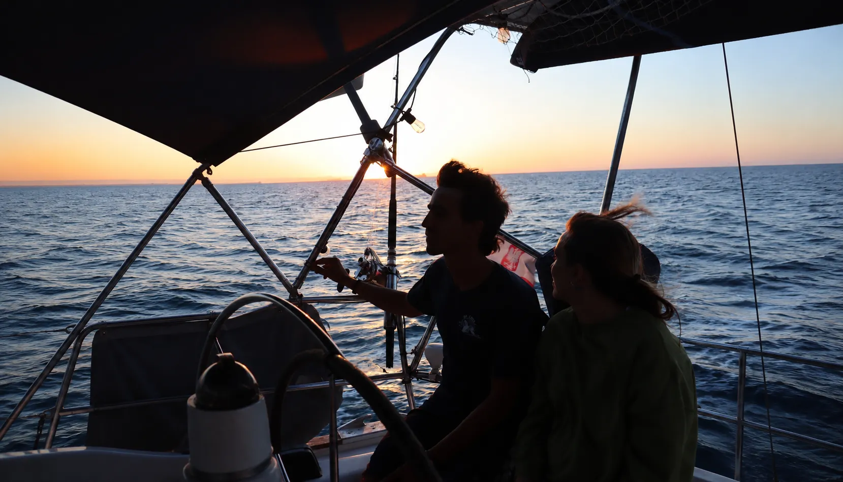 Pareja ajustando cabos y preparando el velero durante una navegación por el Caribe.
