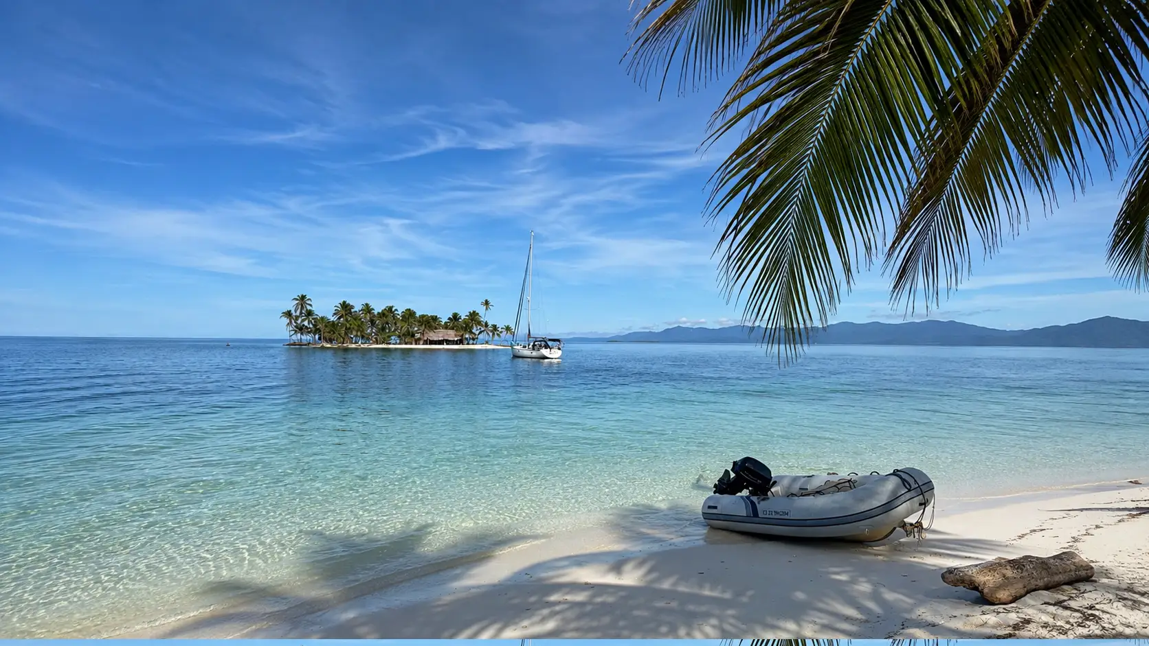 Persona mirando el mar desde la popa de un velero frente a islas tropicales.